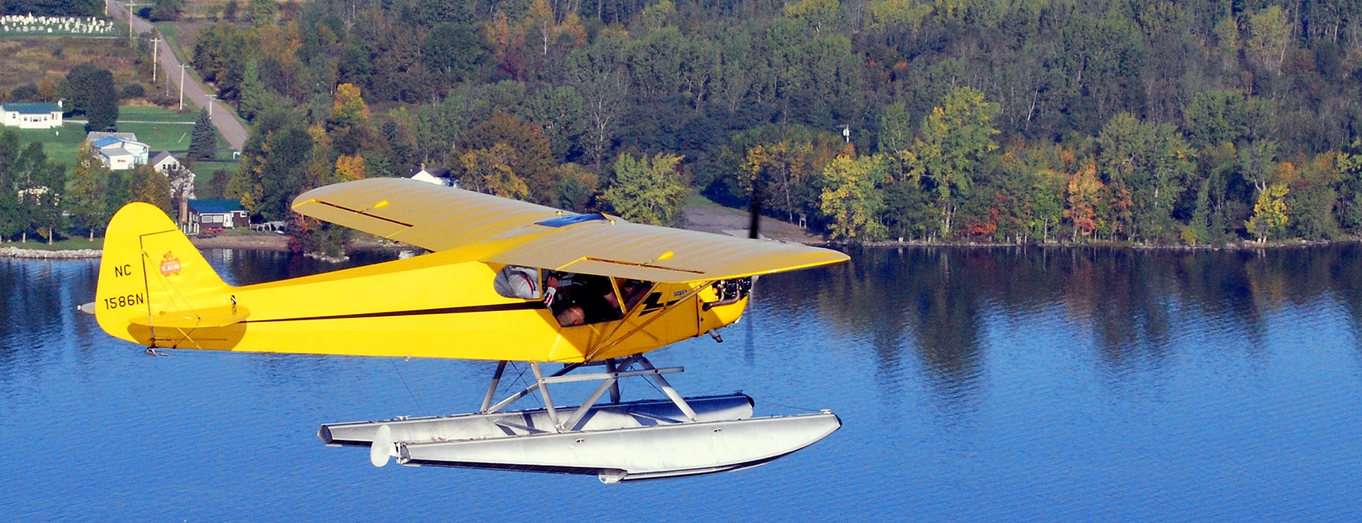 Yellow plane with floats flies about the water