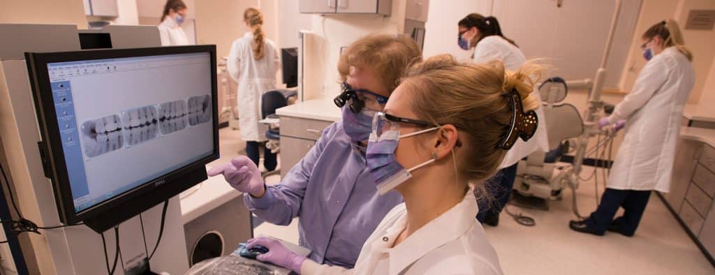 Faculty works with female student looking at dental xrays in the dental hygiene lab in Williston