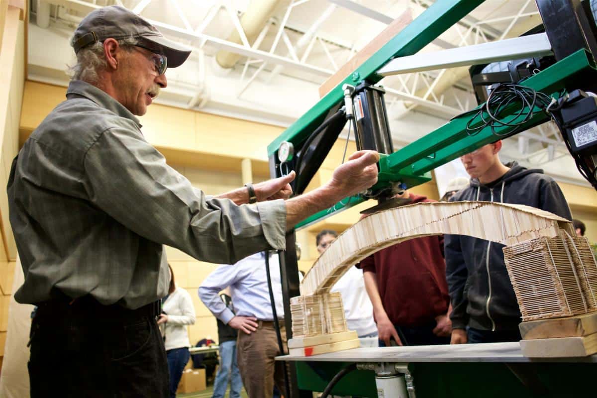 Geoff Finkles readies the machine to break the Popsicle stick bridges at the Bridge Building competition on the Randolph Center campus