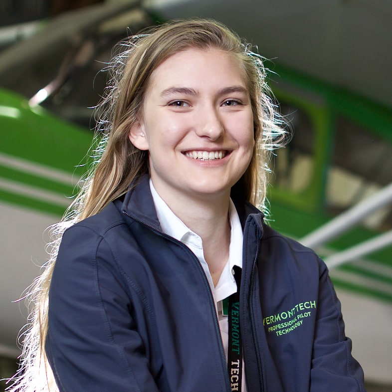 Female student Elisabeth Hoehn smiles in front of the plane that she flies while a student in the professional pilot technology program on the Williston campus.