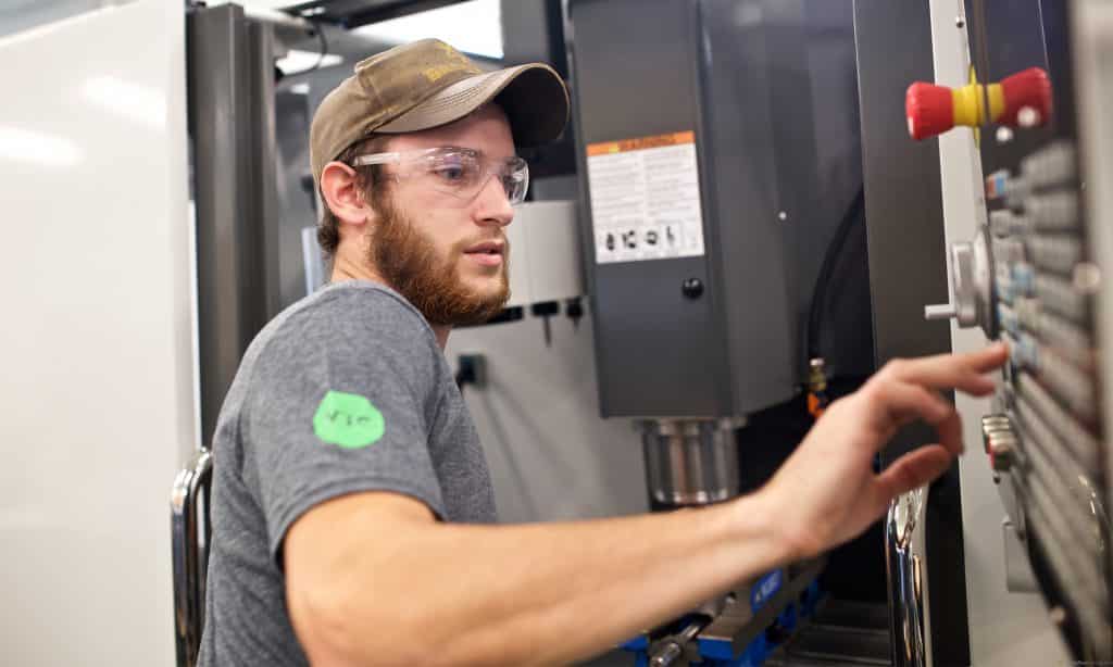 Male student runs a HAAS machine in the mechanical engineering lab on the Randolph Center campus.