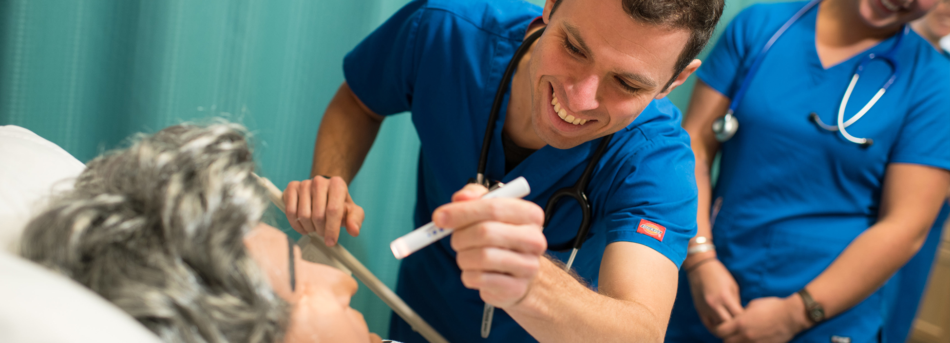 Male nursing student works with female nursing student in the simulation lab on the Williston campus.