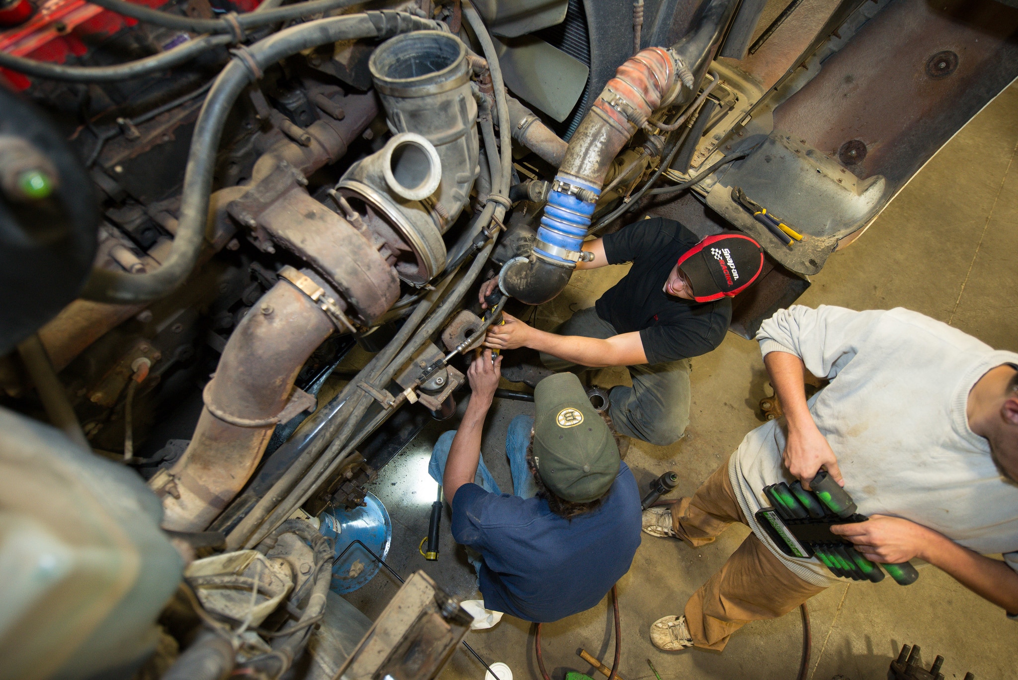 Three Vermont Tech students work on a large truck diesel engine, lab, Randolph Center campus