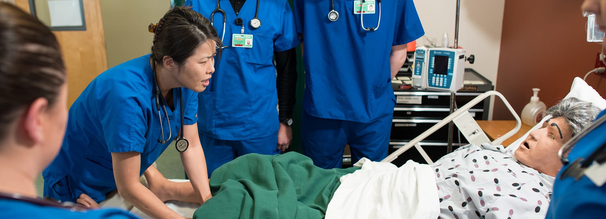 A group of nursing students examines a simulation patient during lab, hands on, Williston campus