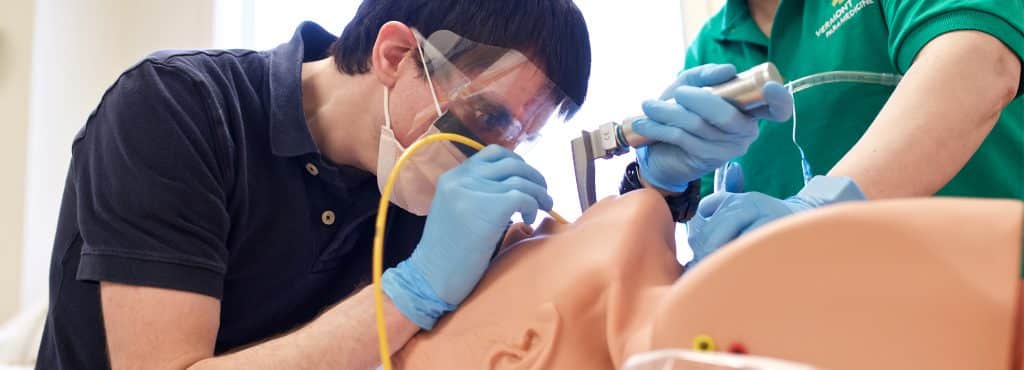 A paramedicine student intubates a simulation patient during lab, Williston campus