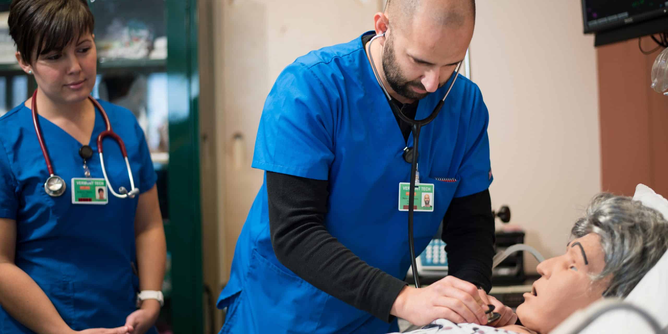 a male nursing student listens to the heartbeat of a simulated patient, hands on, lab