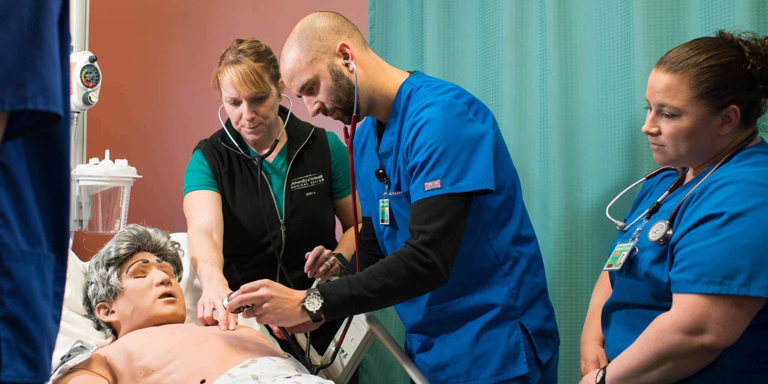 a male nursing student listens to the heartbeat of a simulated patient, hands on, lab