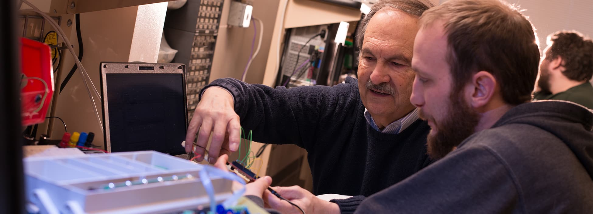 A professor works with an Electrical Engineering Technology student during lab, hands on