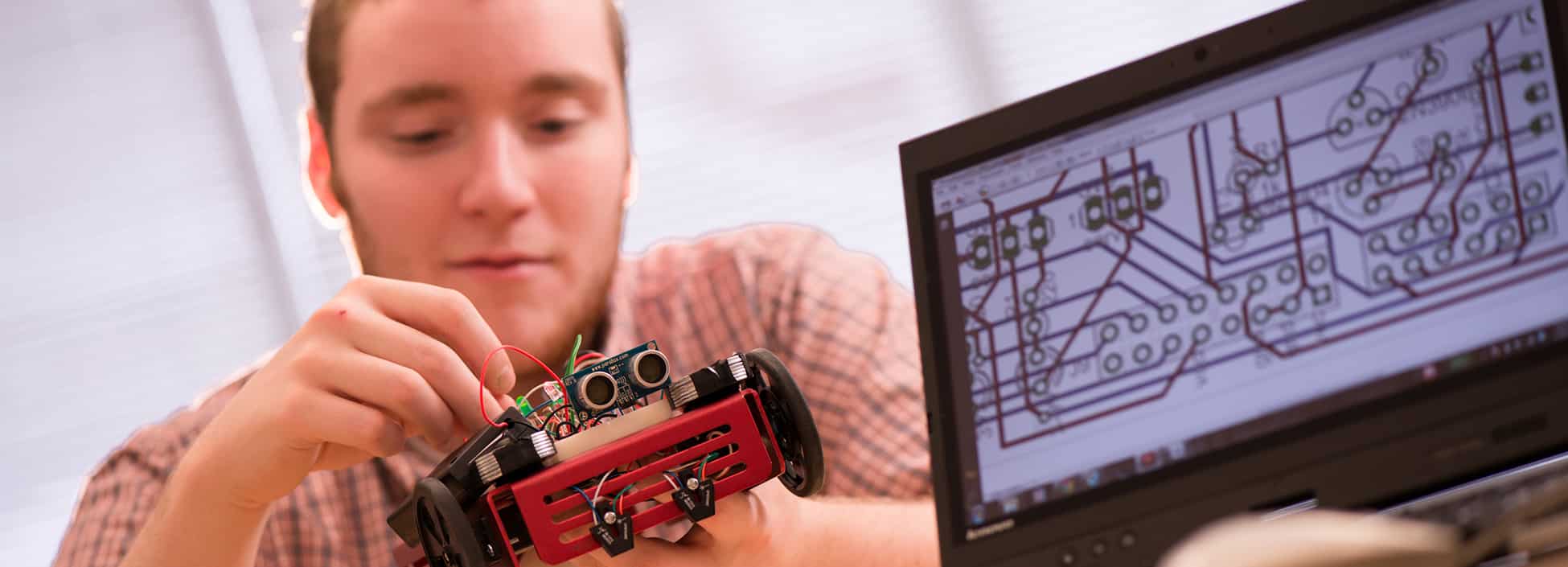 An Electromechanical Engineering Technology students works with a remote car in lab