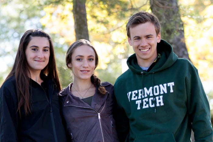 female students, male student, smiling, outside under trees