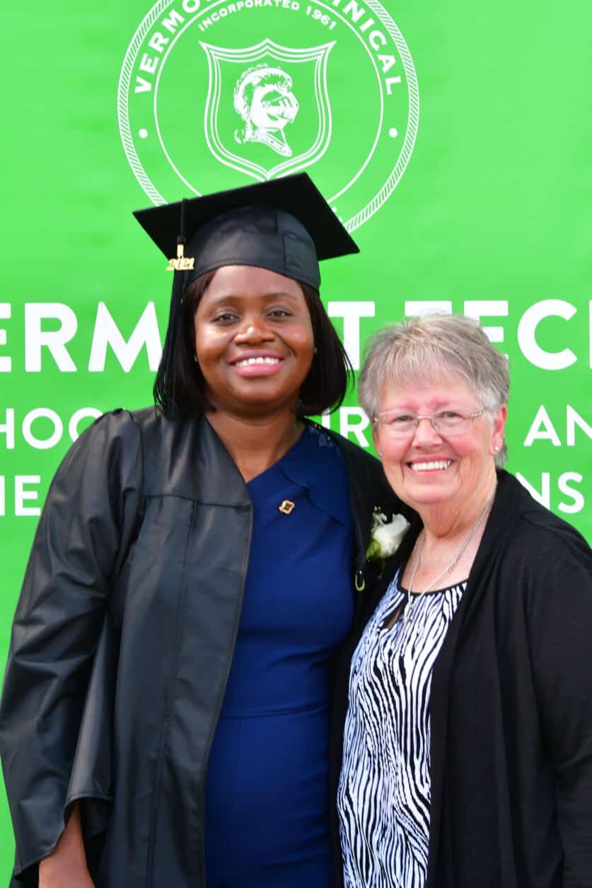 A Practical Nursing student stands in her regalia with her mentor for her pinning ceremony.