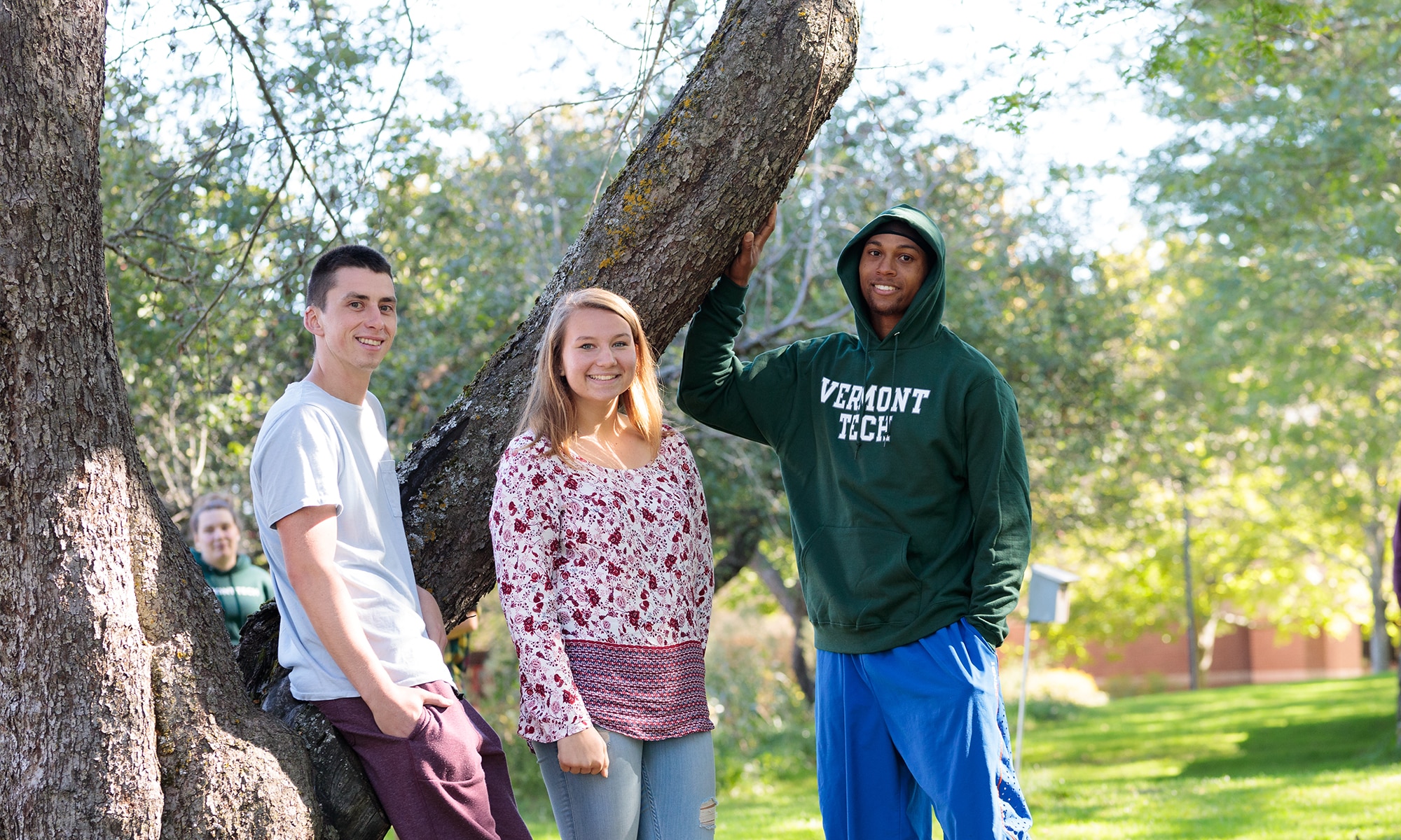 three students stand among the apple trees on the Randolph Center campus