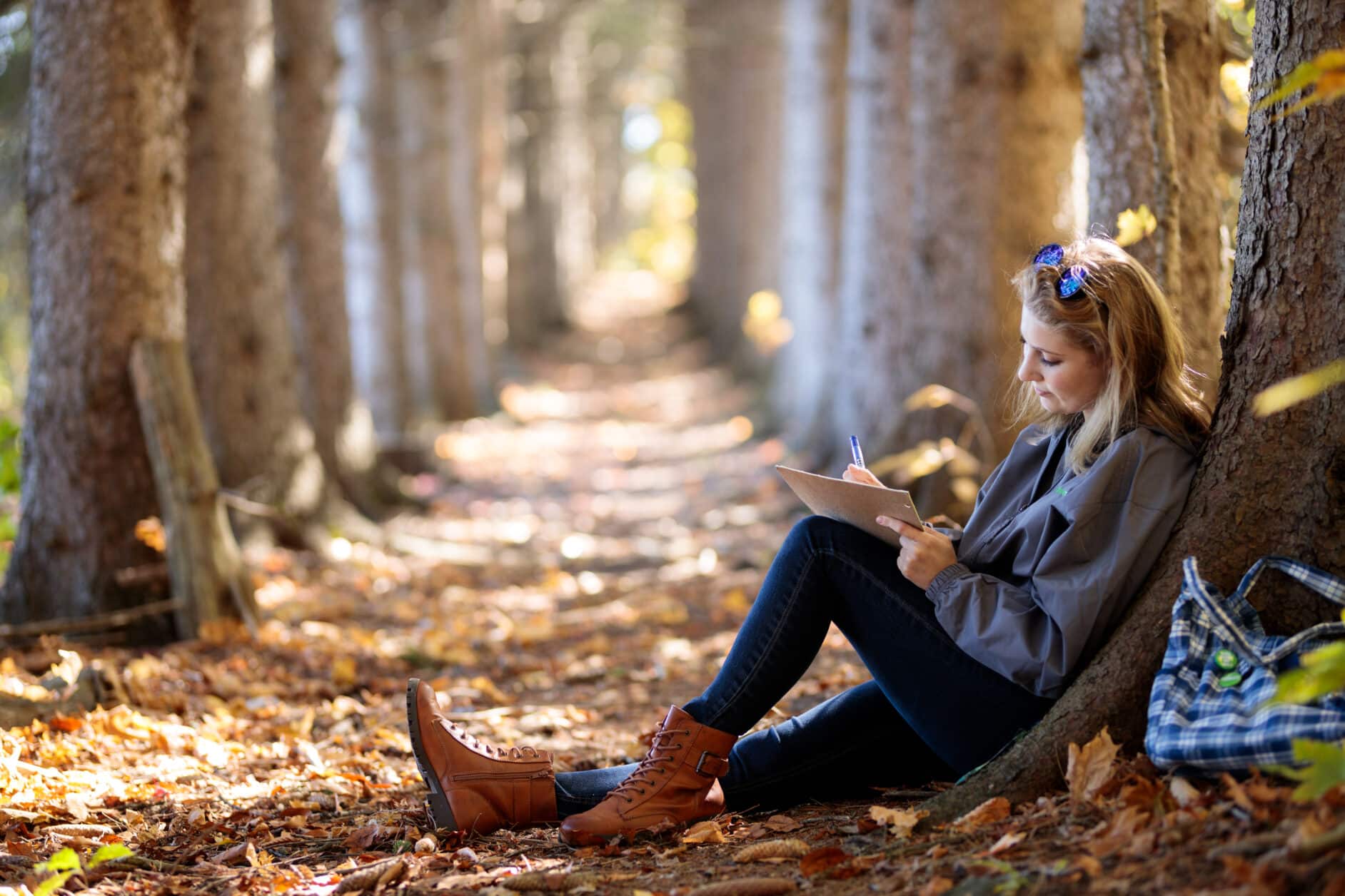 Student sits under tree and works on homework